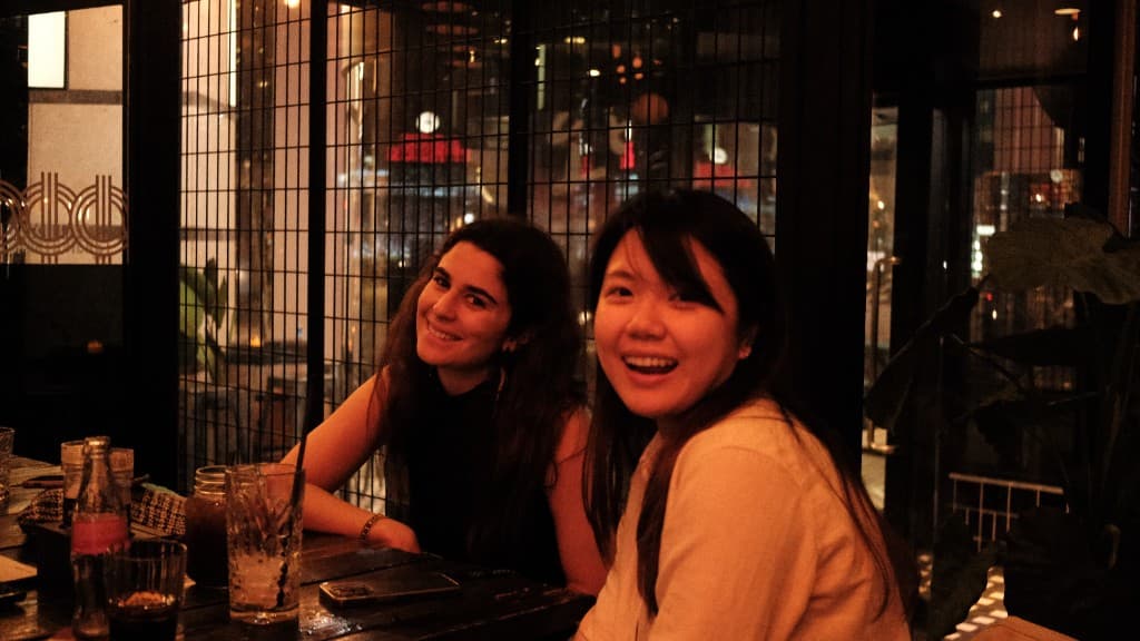 Twee vrouwen glimlachen aan tafel tijdens een avond uit