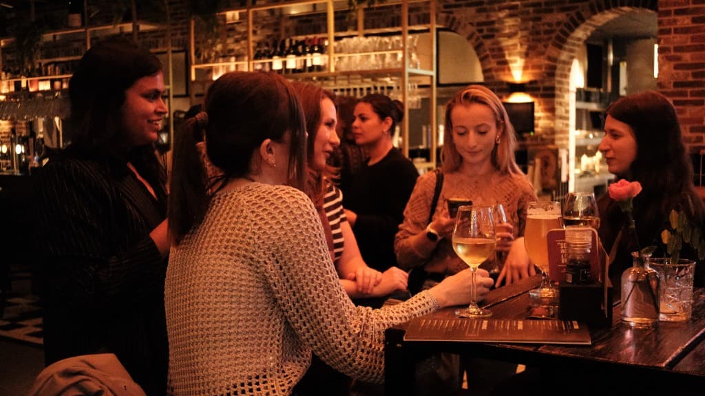 Groep vrouwen aan tafel met wijn en cocktails